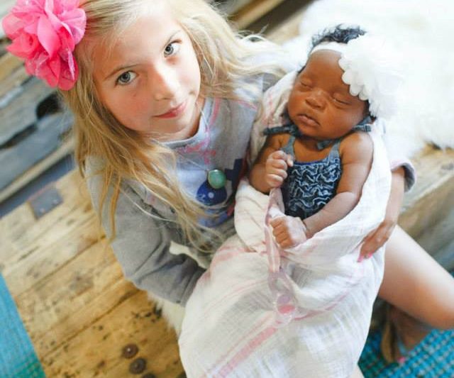 Transracial adoptive sister holding newborn sister