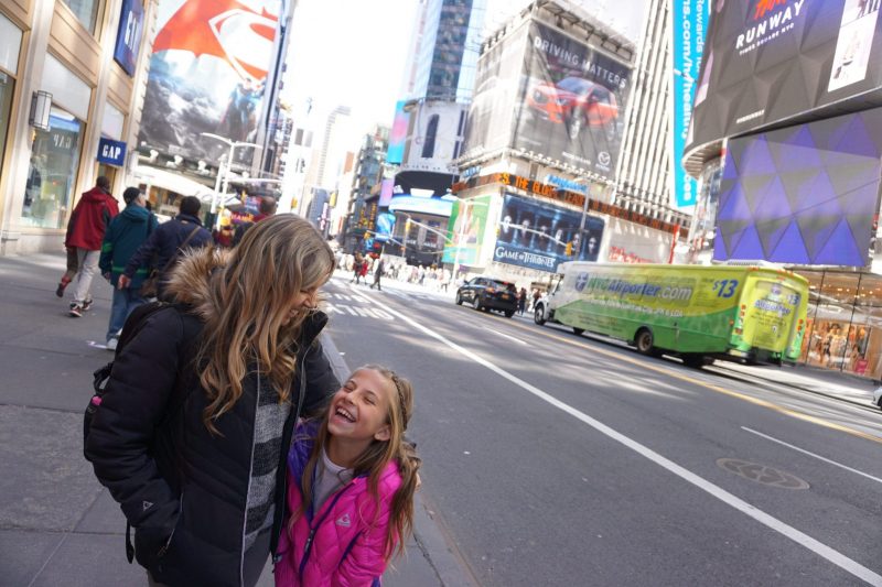 Mon and daughter embracing in time square. Mom and daughter are happy and smiling.