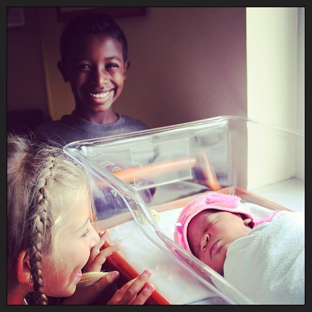 Brother and sister holding newborn. transracial adoptive family. Global Munchkins