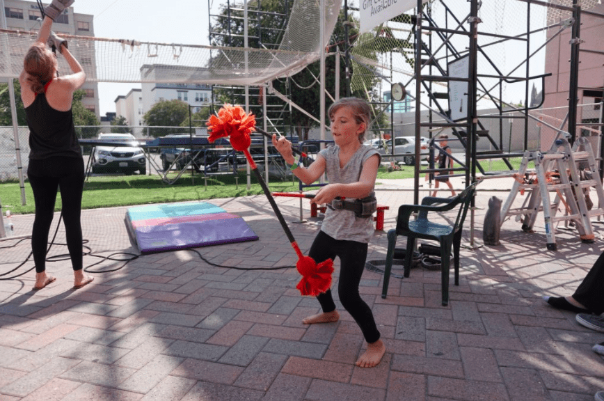 Playing with Devil Sticks at SwingIt Trapeze in Anaheim while waiting for her turn to swing | Global Munchkins